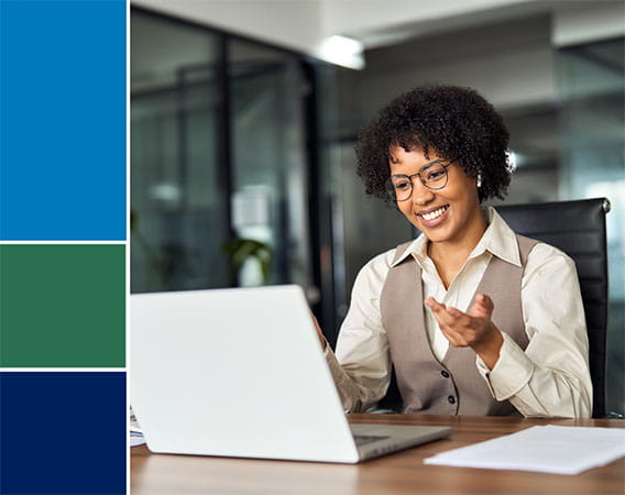 Woman at her desk, looking a laptop, with a smile on her face
