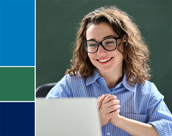 Young woman smiling, facing her laptop, hands clasped
