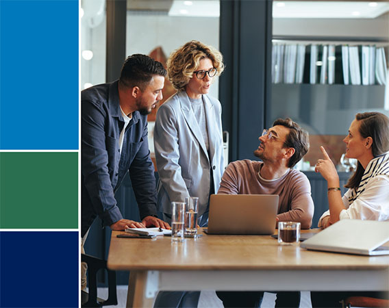Image of four people at a meeting, two are standing, two are sitting