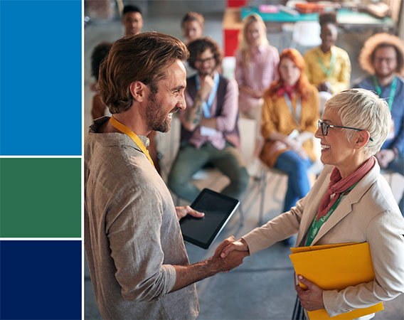 Man and woman shaking hands in front of crowd of employees