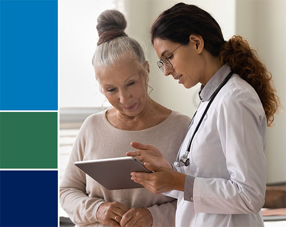 Female doctor talking to female patient. They are both looking a digital tablet device.