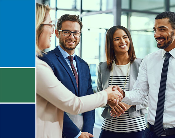 Four people in a group, two are shaking hands, all are smiling