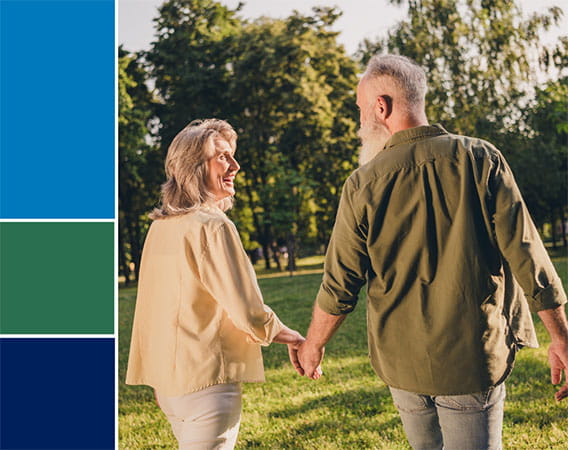 Older woman and man walking in the park, holding hands, smiling at each other