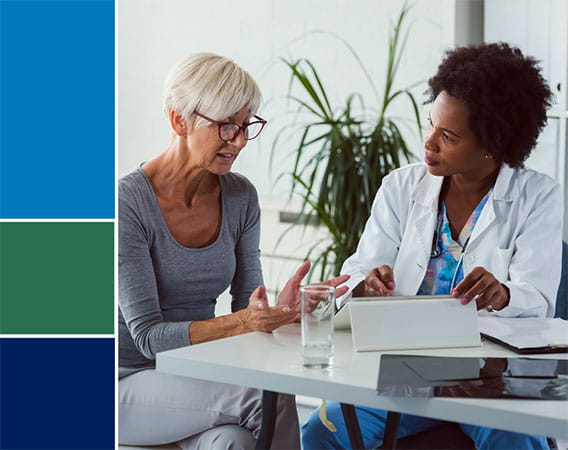 Female doctor talking to female patient, both are seated at a table