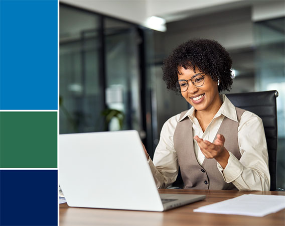 Woman at her desk, looking a laptop, with a smile on her face