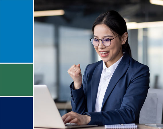 Asian woman sitting at her desk with a laptop on the table, she is smiling